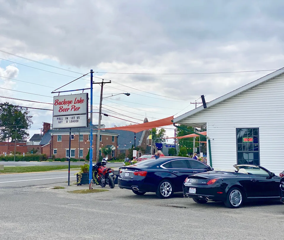 A line of cars parked at a small building.