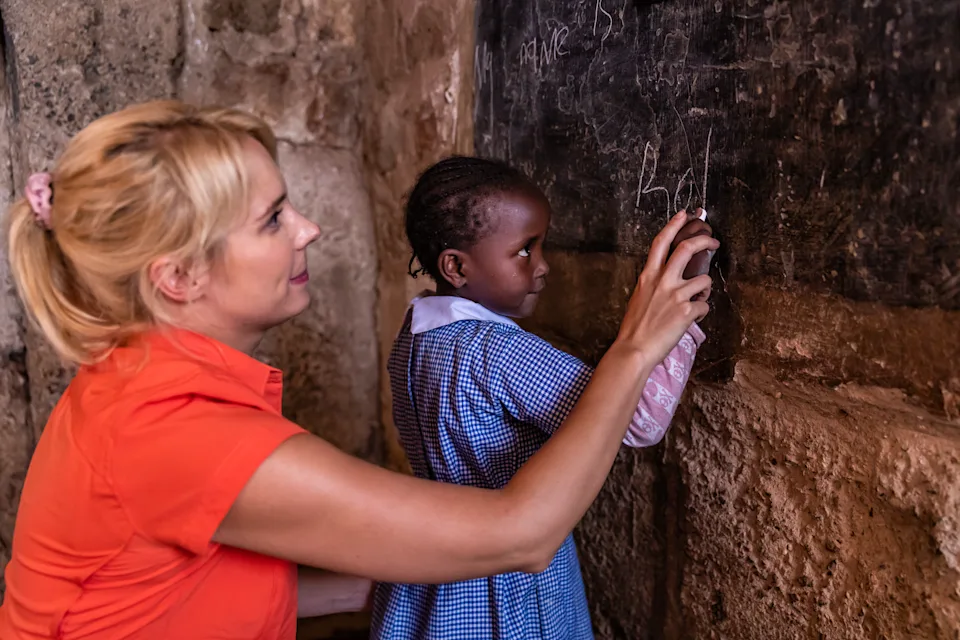 Caucasian female volunteer teaching in orphanage in Kenya. There is no light and electricity inside the classroom. Around 20-30 orphans live in this orphanage which is located near Nairobi.