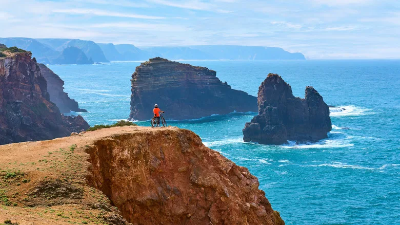 Woman cycling on the the rocky cliffs of the Vicentina coast of Portugal