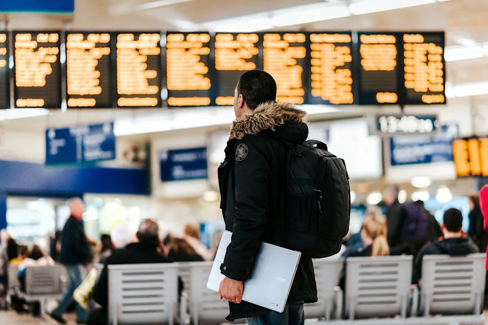 Man standing in airport looking at flight schedule