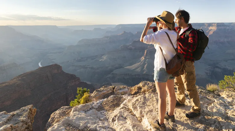 A couple on the edge of the Grand Canyon with binoculars