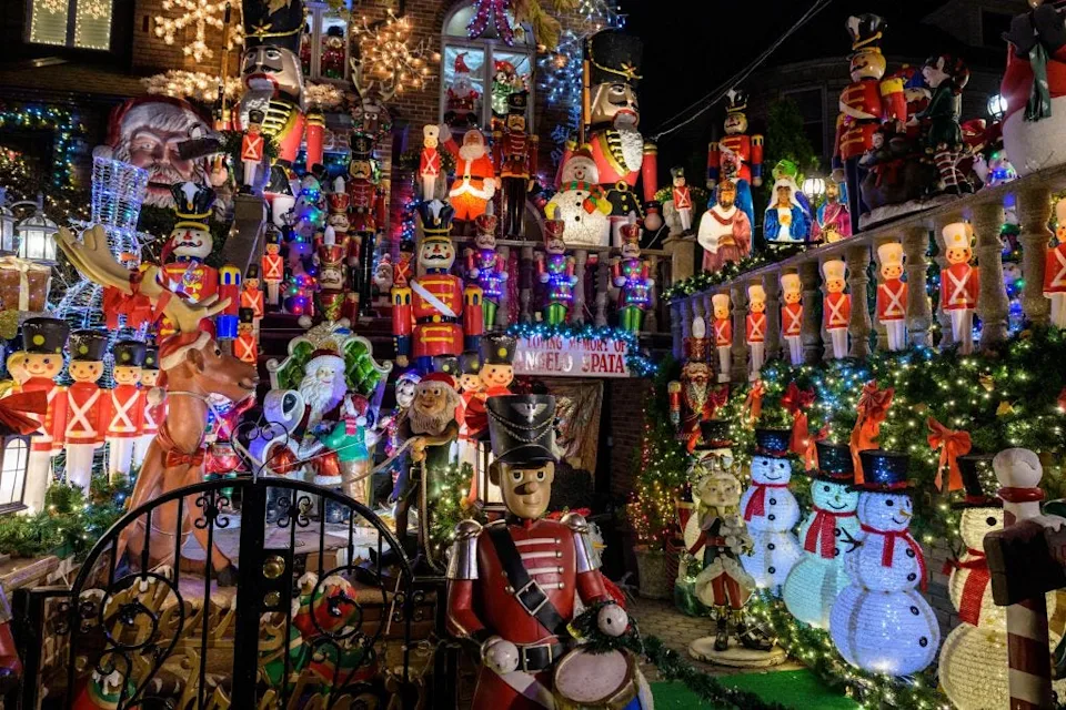 a house and small front yard completely covered with christmas lights and decorations including ornaments blow molds and other figures of snowmen, toy soldiers, santa, and the three wise men