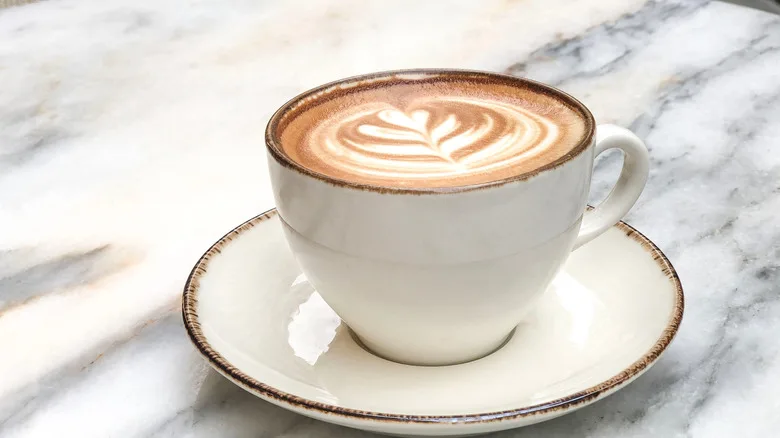 A cup of coffee with latte art on a marble surface