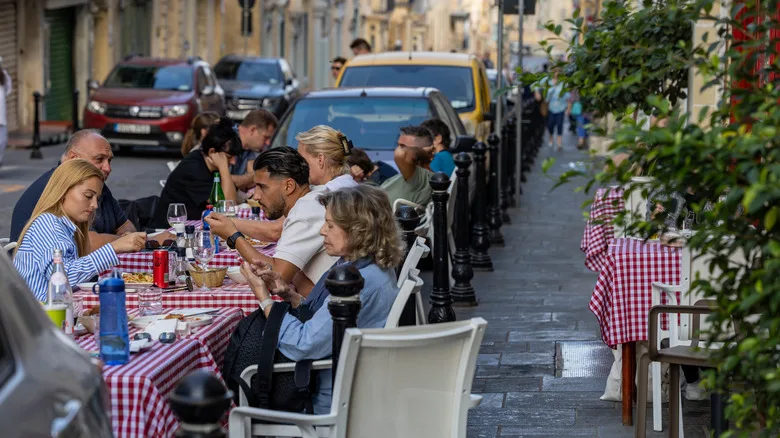 People eating at tables by a sidewalk