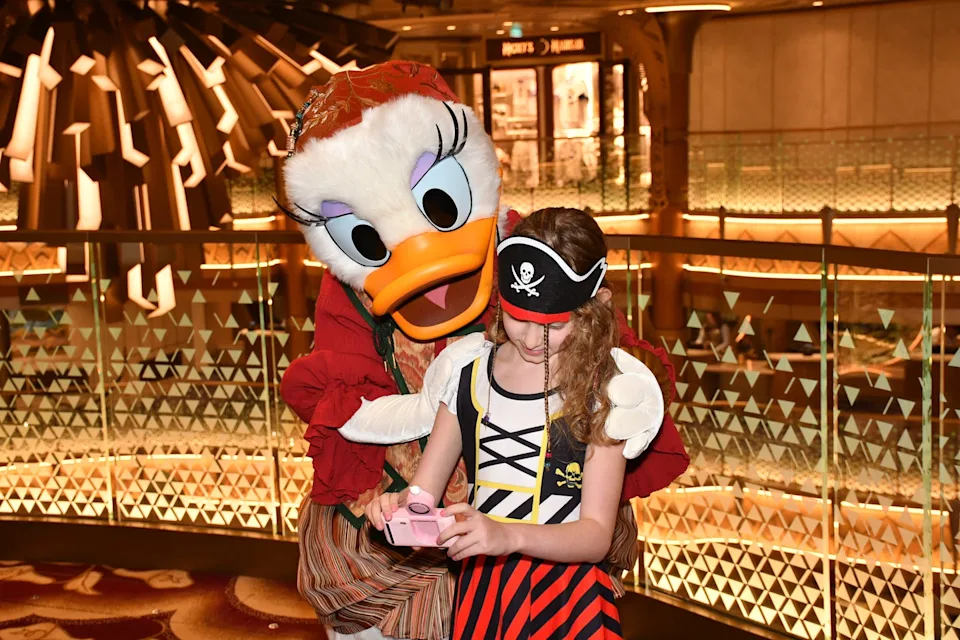 a child taking a selfie with daisy duck, both dressed in pirate costumes