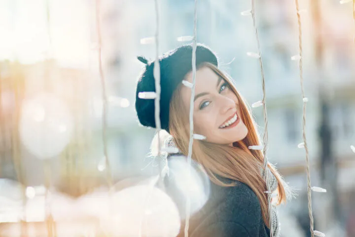 Beautiful woman looking through festivity lights, with sunlight in her face.