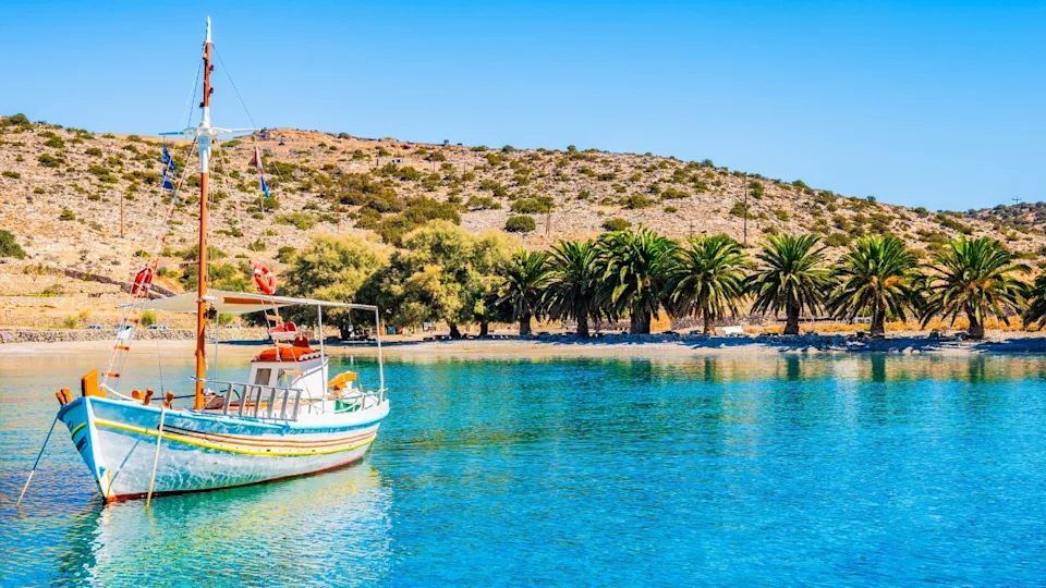 Fishing boat on azure sea and palm trees on idyllic Panormos beach, Naxos island, Cyclades, Greece
