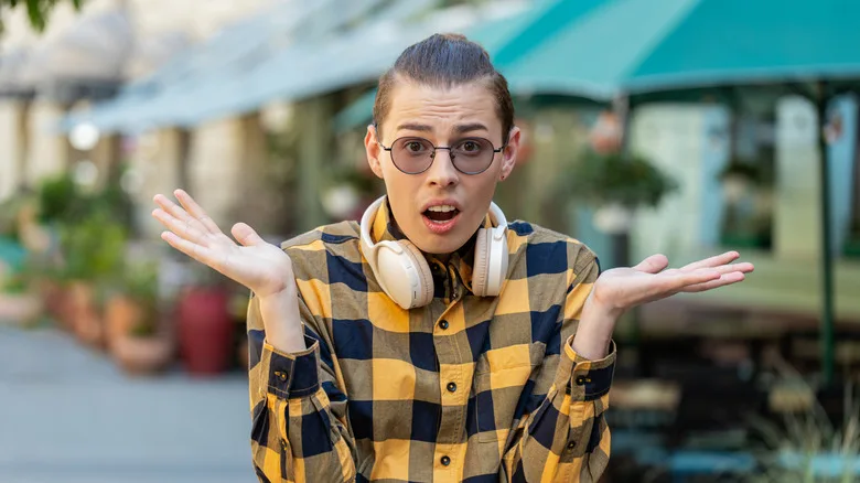 Confused-looking person shrugging and holding their hands up