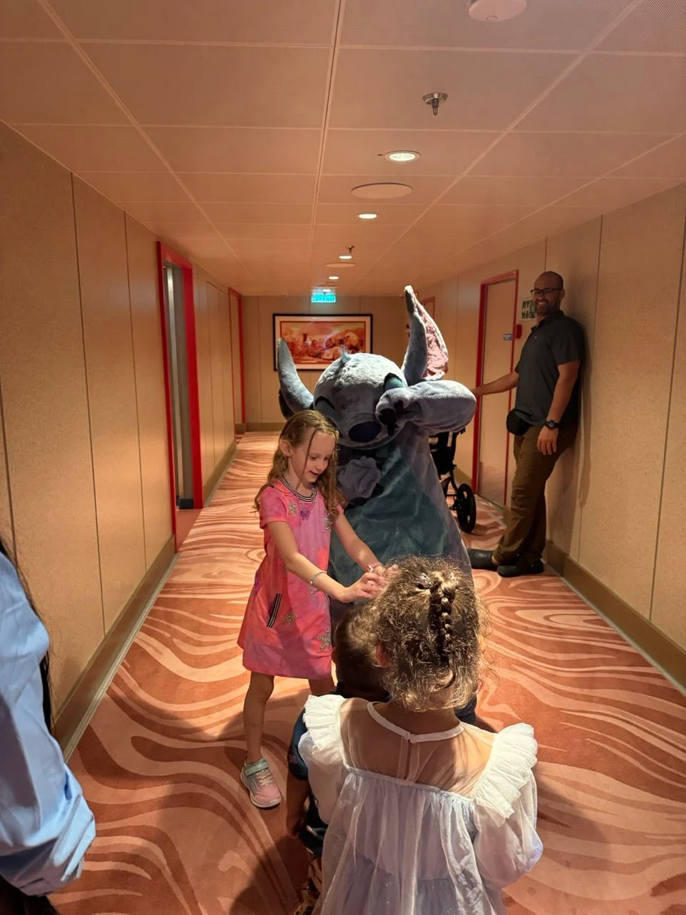 children interacting with a cartoon character in a hallway