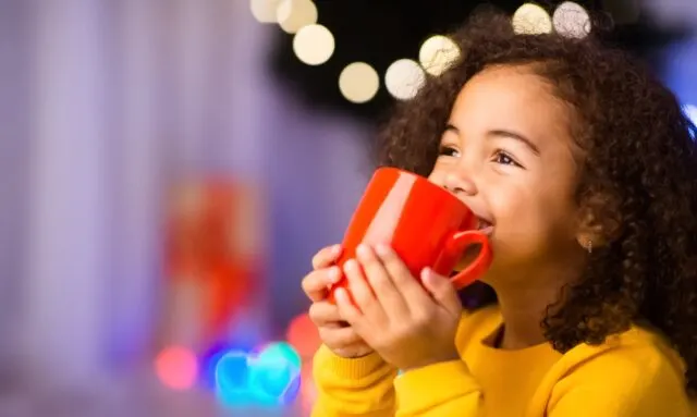 Cute young girl smiling, drinking hot chocolate