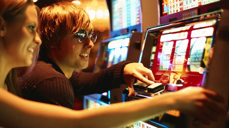Two stylish young people playing a slot machine