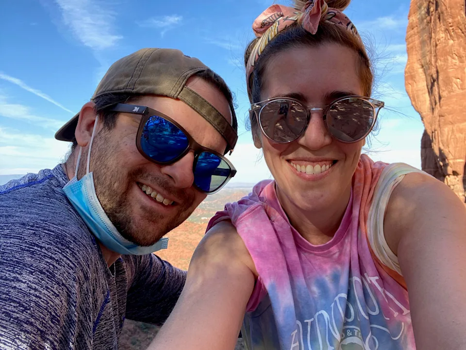 A man and woman posing beside a rock pillar.