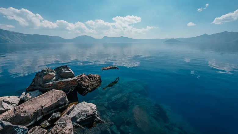 Woman dives into crystal clear Crater Lake in Oregon