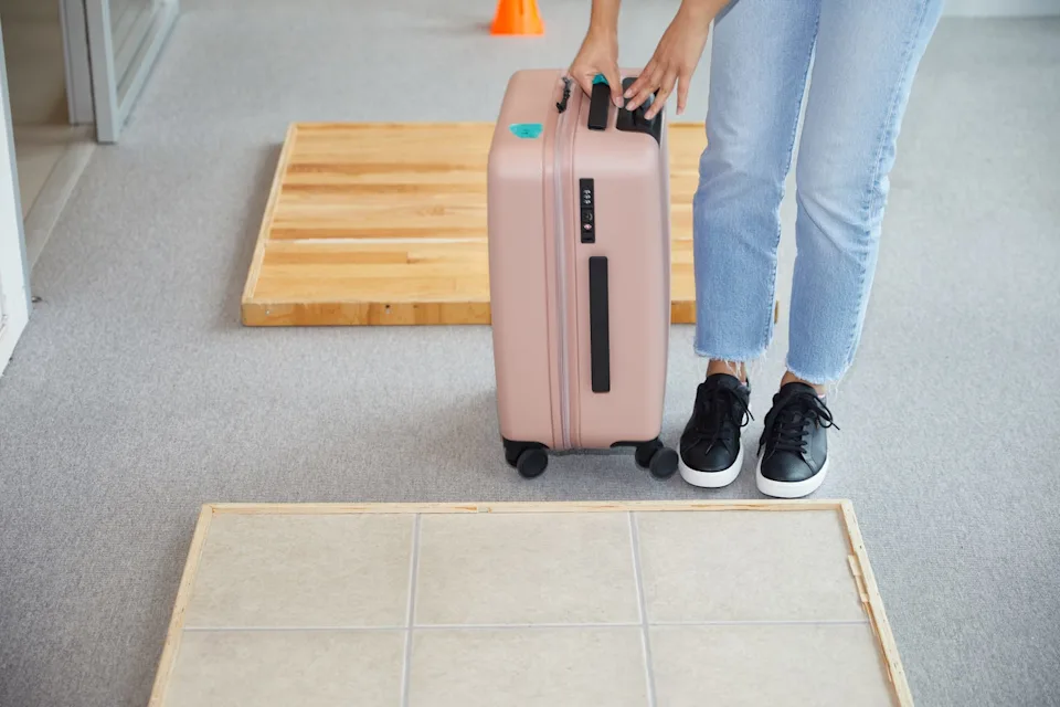 a person wheels luggage over different types of flooring