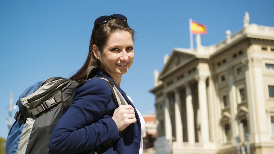 Pretty young female tourist with backpack in front of the building in Barcelona city, Spain.