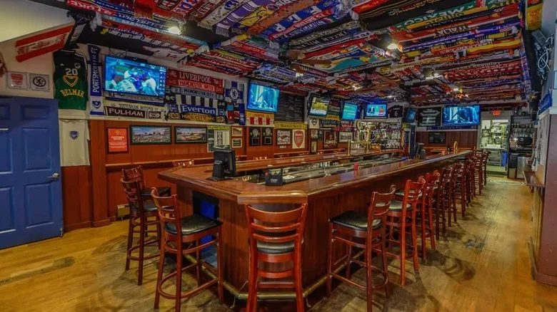 Interior of D'Arcy's Tavern with wooden bartop and soccer scarves adorning ceiling