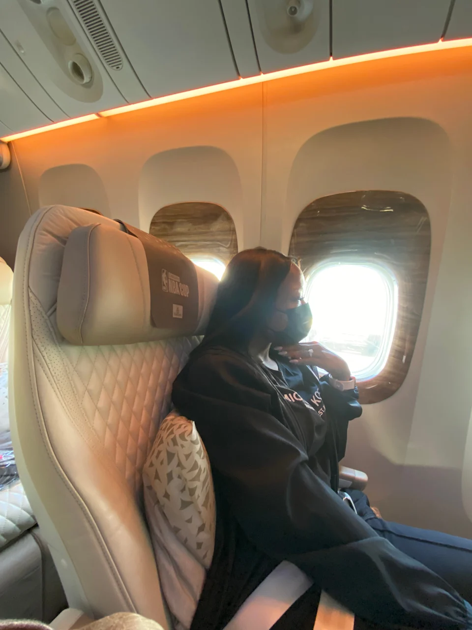 I am seated in an Emirates Premium Economy window seat with soft lighting, leaning back comfortably as the cabin prepares for departure.