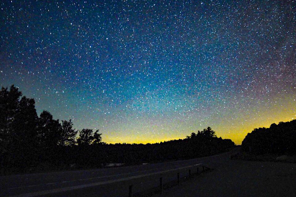 The Northern lights peek through the starry sky above the Adirondack Mountains
