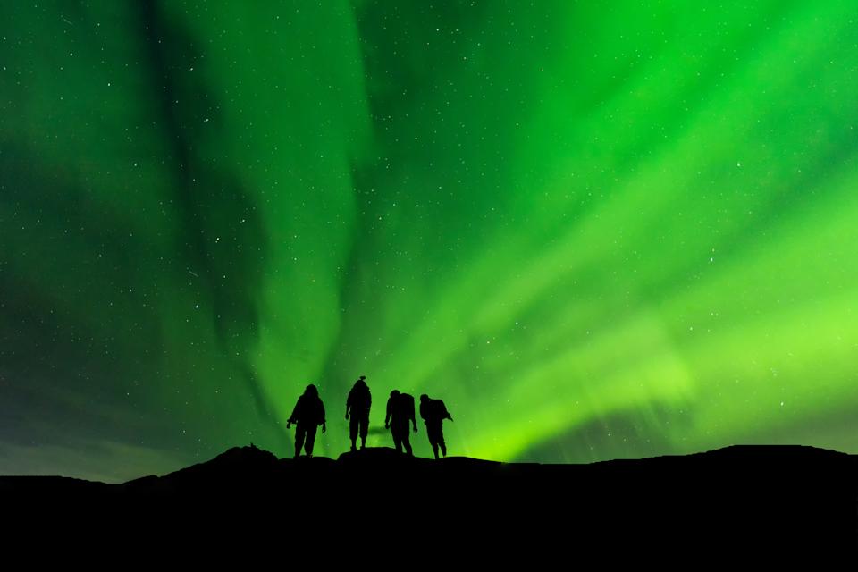 Silhouette group standing on top of peak mountain and Aurora light .success, winner, leader and Teamwork concept .