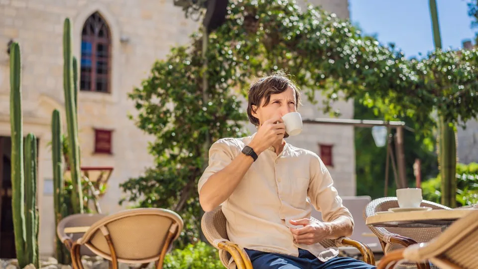 Young man tourist drinks cofee in the old town of Budva. Travel to Montenegro concept