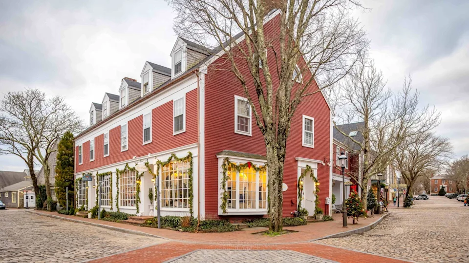 A red building on a cobblestone street decorated for Christmas in Nantucket, Mass.
