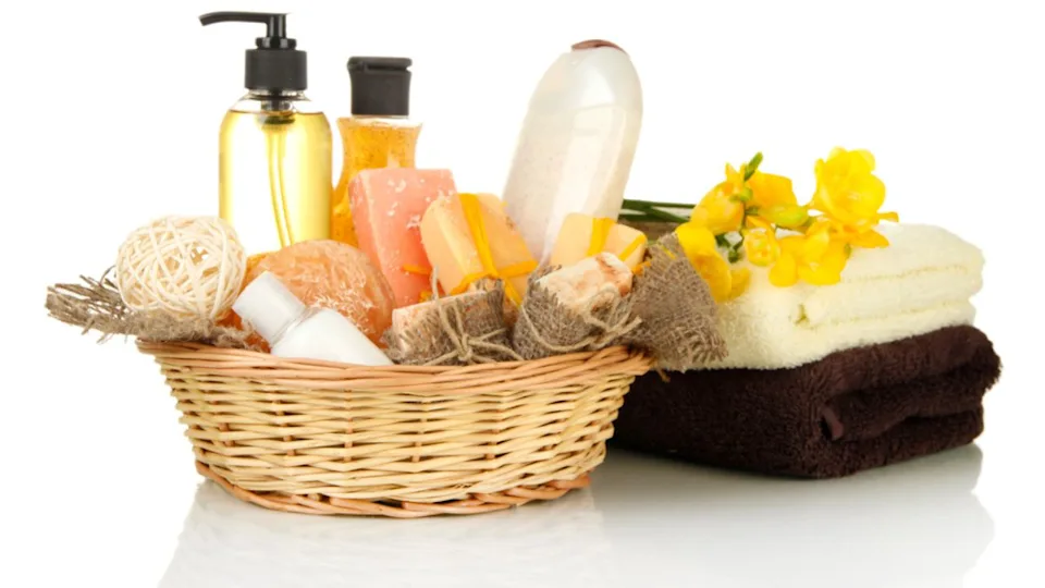 Composition of cosmetic bottles and soap in basket, isolated on white
