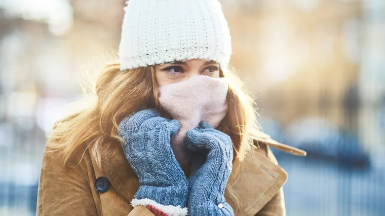 Woman wearing gloves and a wooly hat with a scarf wrapped around her face