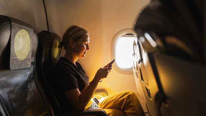 A woman using a smart phone on a plane