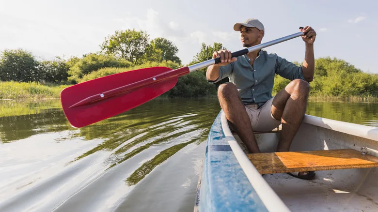 Man paddling a canoe in a marsh