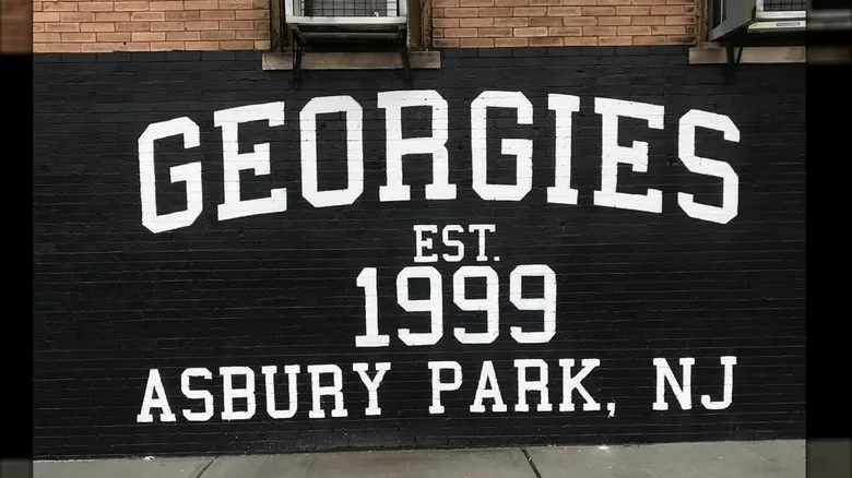 Georgies Bar mural painted with white letters on black background on brick wall
