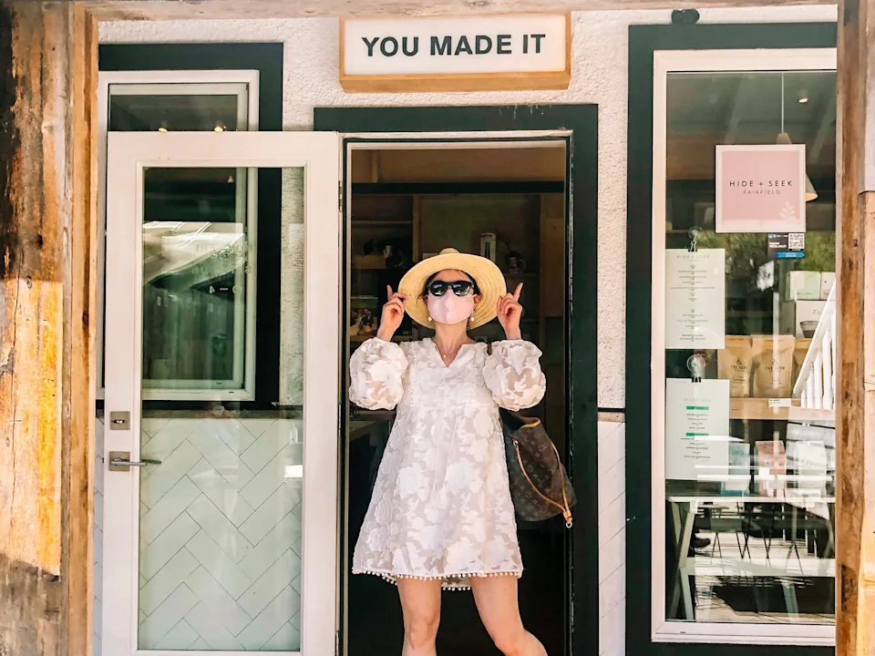 simone posing under a sign that reads you made it at hide and seek coffee shop in victoria canada