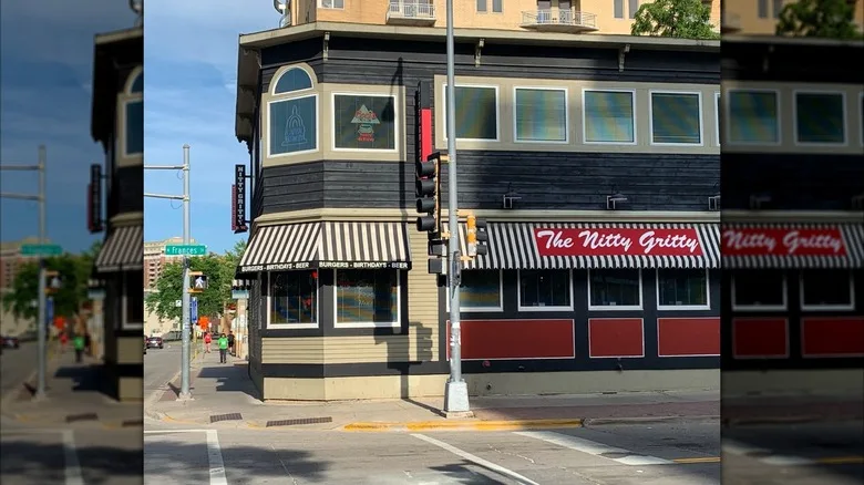 Exterior of Nitty Gritty with a striped white and black awning and a red sign