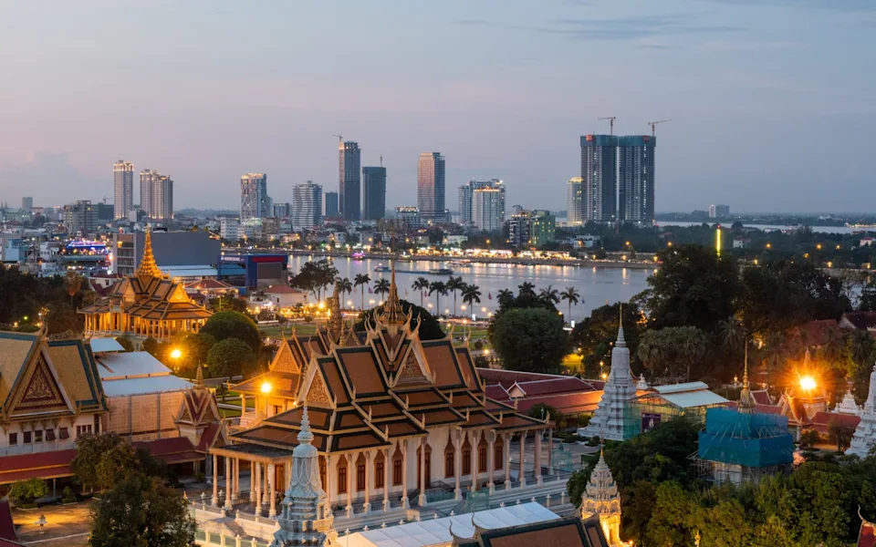 Night view of Phnom Penh's skyline, where traffic, commuters, and tourists move through streets lined with tall hotels, apartments, and shopping malls.