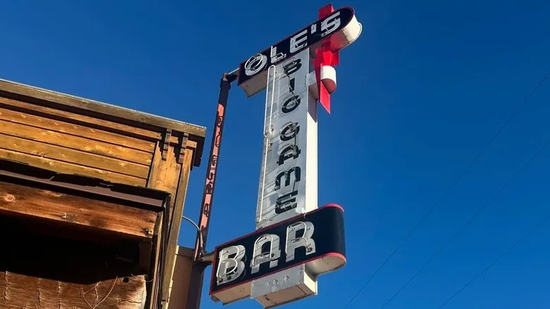 A vintage sign saying Ole's Big Game Bar against a bright blue sky