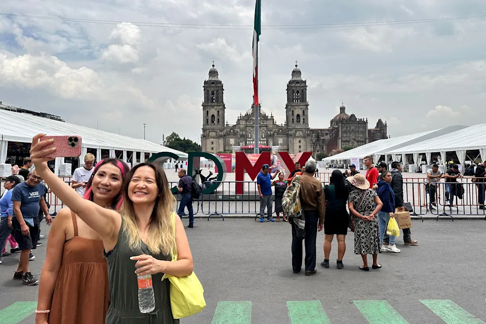 Tourists pose for a selfie in front of the facade of the Metropolitan Cathedral in Mexico City on August 4, 2023.