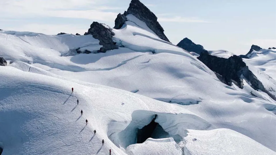 Drone shot of hikers in a line on a glacier on the Coastal Mountains of British Columbia, Canada