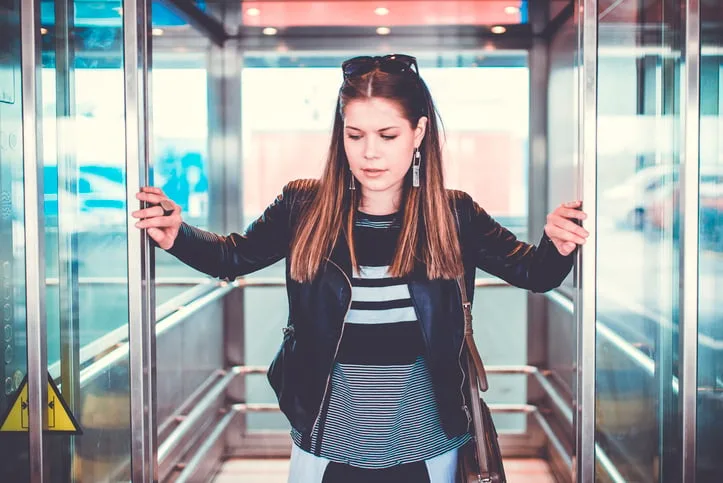Woman holding open elevator doors.