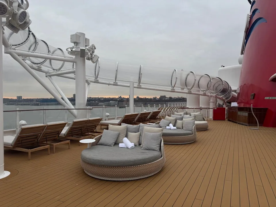 outdoor lounge area on a cruise ship with seating and a view of the water