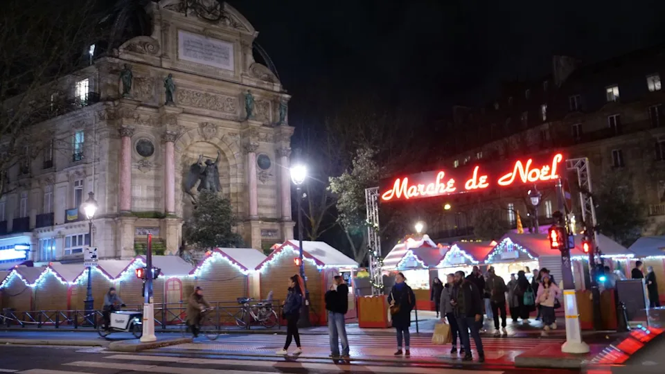 A view of the Saint Michel fountain by night with a Christmas market. Paris, France - December 18, 2024