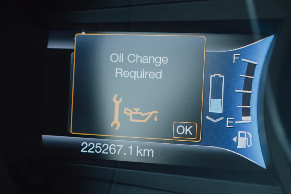Digital Car Dashboard Displaying Oil Change Required Maintenance Warning with Wrench and Oil Can Symbol, Odometer Mileage, Fuel Gauge and Headlight Indicators