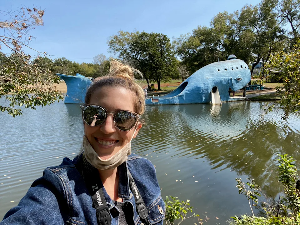 A woman posing in front of a sculpture of a blue whale.
