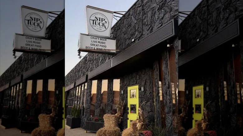 Exterior of Nip n Tuck Bar & Grill with white sign over doorway