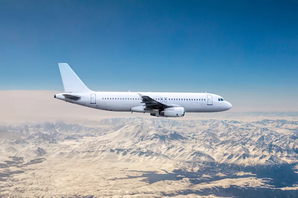 White modern airplane flying over snow covered mountains