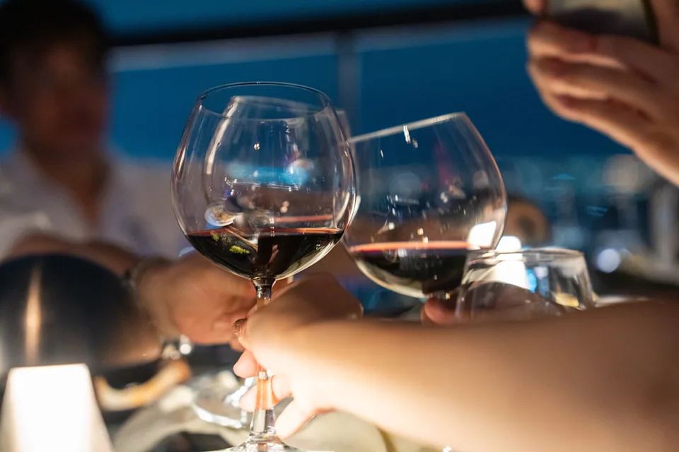 People clinking glasses with wine in a celebratory toast, focusing on teamwork and success in a work setting