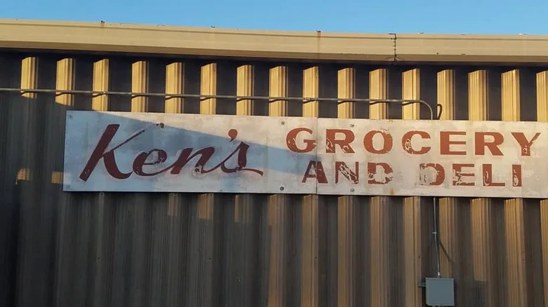 An old metal wall with an old sign saying Ken's Grocery and Deli