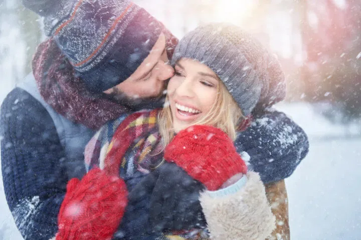 Couple wearing knits in the snow.