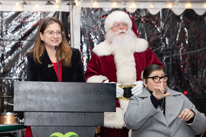 woman in front of podium with santa behind