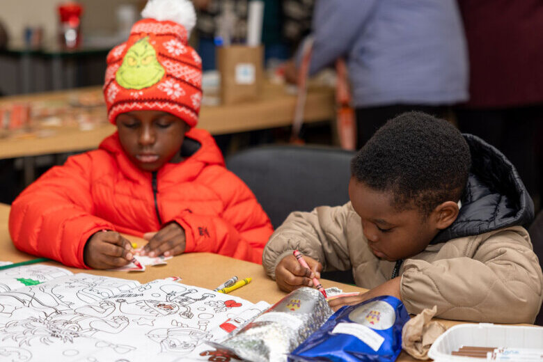 two children coloring at a table wearing winter clothing