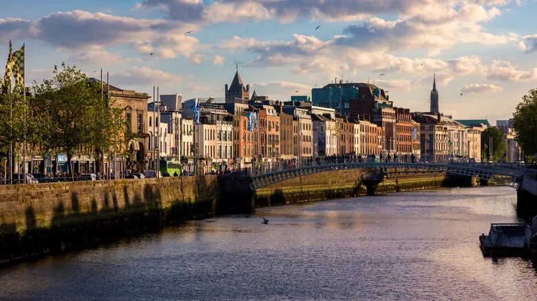 Pedestrians cross the Ha'penny Bridge over the River Liffey in Dublin, at sunset.
