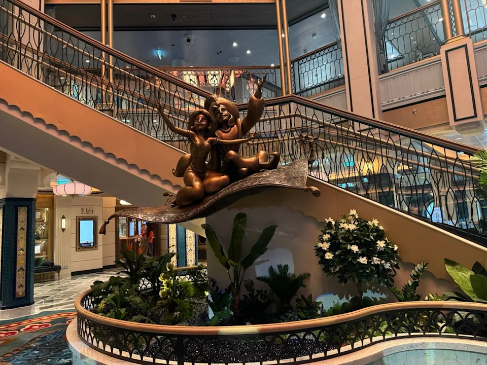 sculpture of characters on a magic carpet in a grand atrium